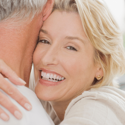 Older woman smiling, hugging husband, representing early detection in women's health